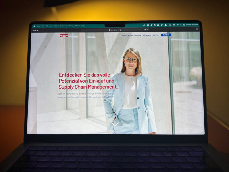 Die amc-Startseite auf einem Laptop vor warm beleuchtetem Hintergrund